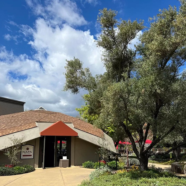 Napa Cellars tasting room with a cloudy blue sky behind it and bright green trees