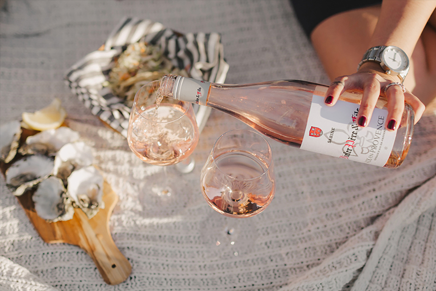 women pouring a glass of bieler sabine rose next to a plate of oysters