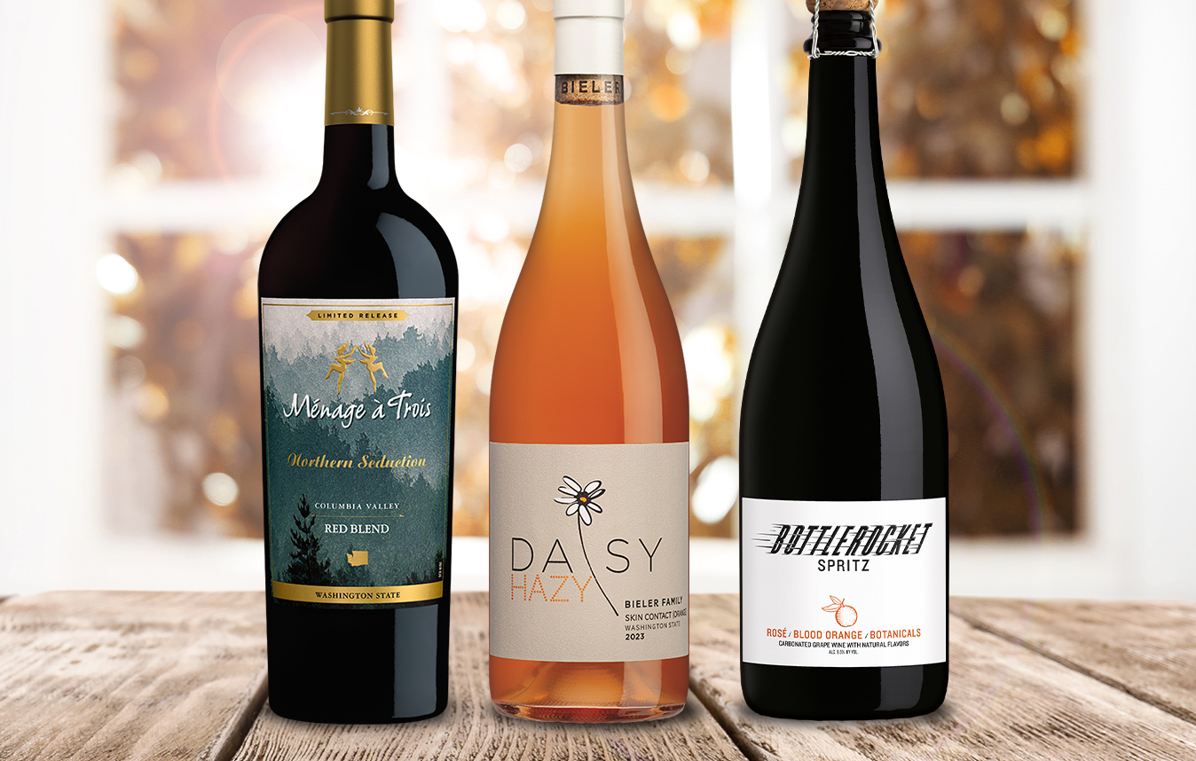 lineup of new arrival wines in front of a window with fall leaves: menage a trois northern seduction, daisy hazy, and bottlerocket spritz