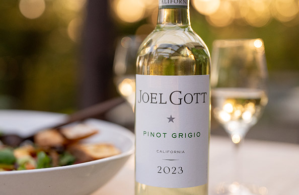 bottle of 2003 Joel Gott California Pinot Grigio with a glass of wine and a white bowl of salad in the background